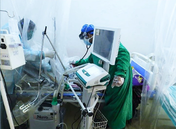 Severe COVID-19 patient on a ventilator, cared for by staff in protective gowns